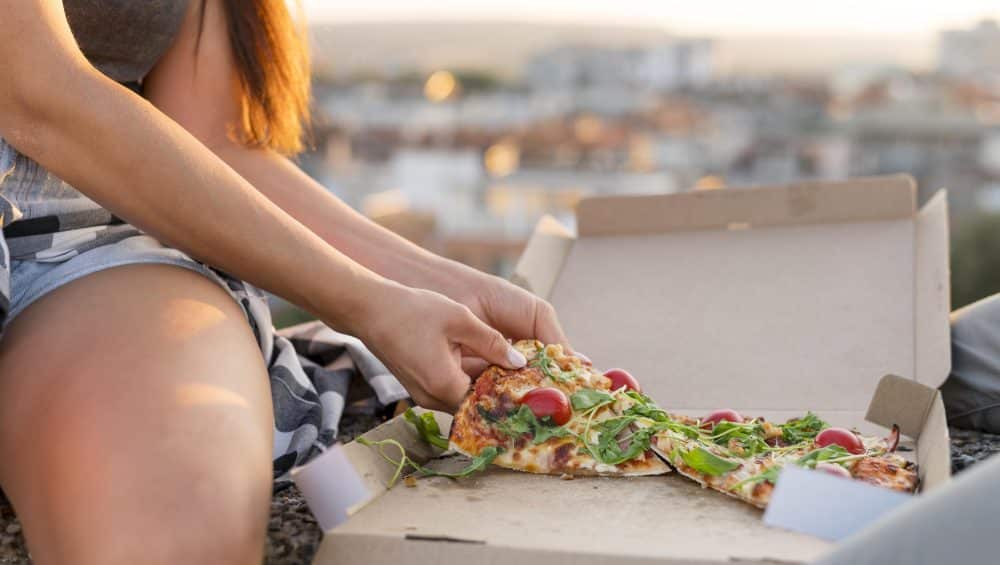 femme manger pizza dehors