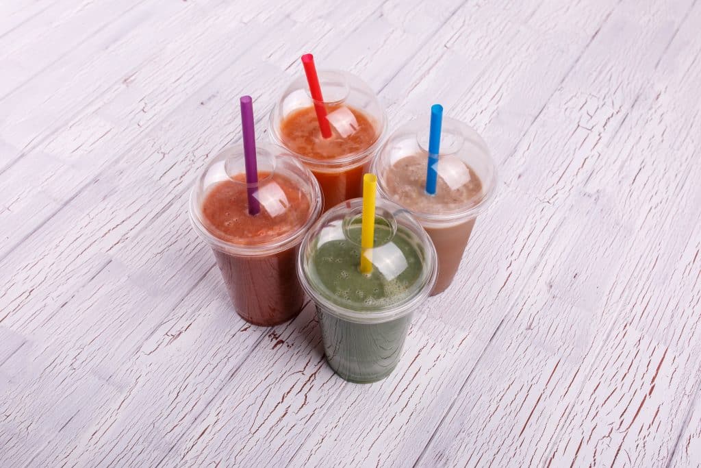 quatre smoothies colores utiles sains dans tasses plastique